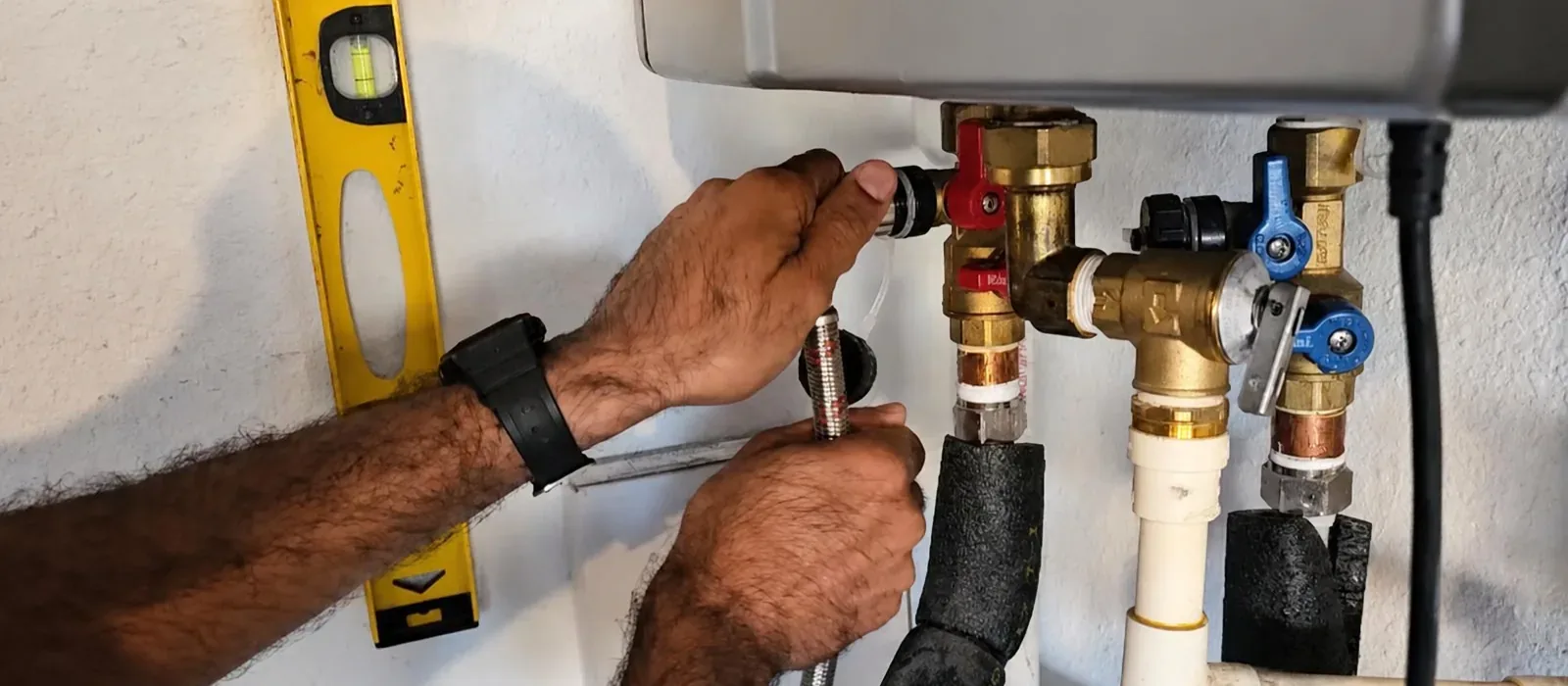Hands connecting fittings on a tankless water heater
